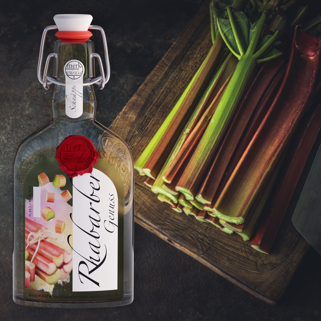 Rhabarbergenuss-Flasche neben frischen Rhabarberstangen auf einem Holzbrett