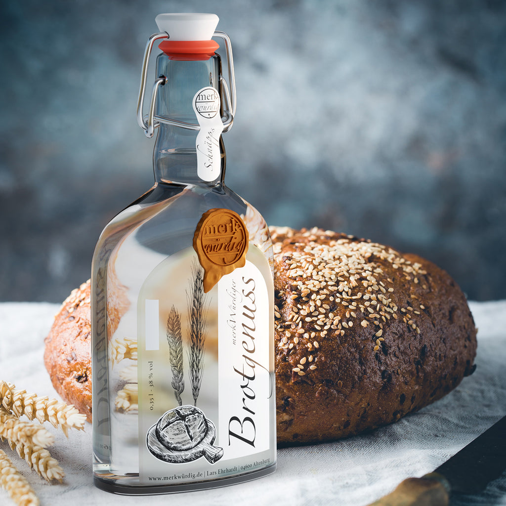Brotgenuss-Flasche vor einem Sesambrot auf hellem Leinen